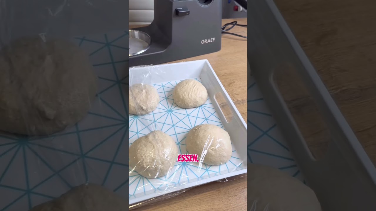 Palline di pasta in un vassoio coperte con pellicola trasparente, elettrodomestico GRAEF sullo sfondo.