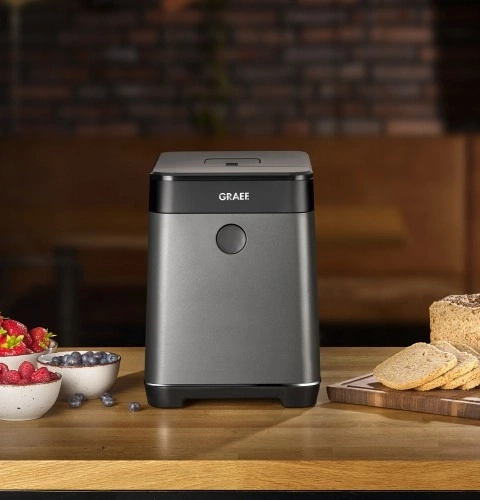 Gray kitchen machine with fruit and bread on a wooden table