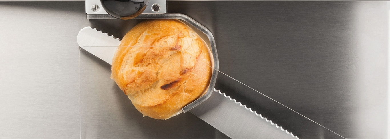 Brötchen in einer Brotschneidemaschine. Nahaufnahme eines Brotes, das geschnitten wird.