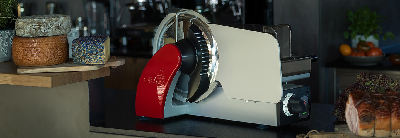 Cheese and meat with a slicer in a kitchen setting.