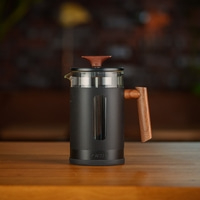 Caffettiera con manico e coperchio in legno su tavolo di legno, logo GRAEF.