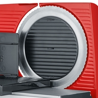 Close-up of a red meat slicer showing the blade and controls.