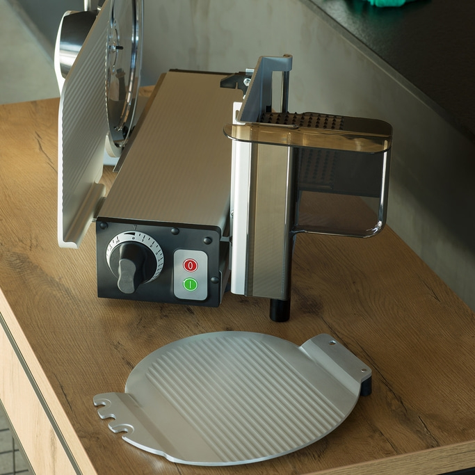 Meat slicer on wooden table with accessories and buttons, close-up