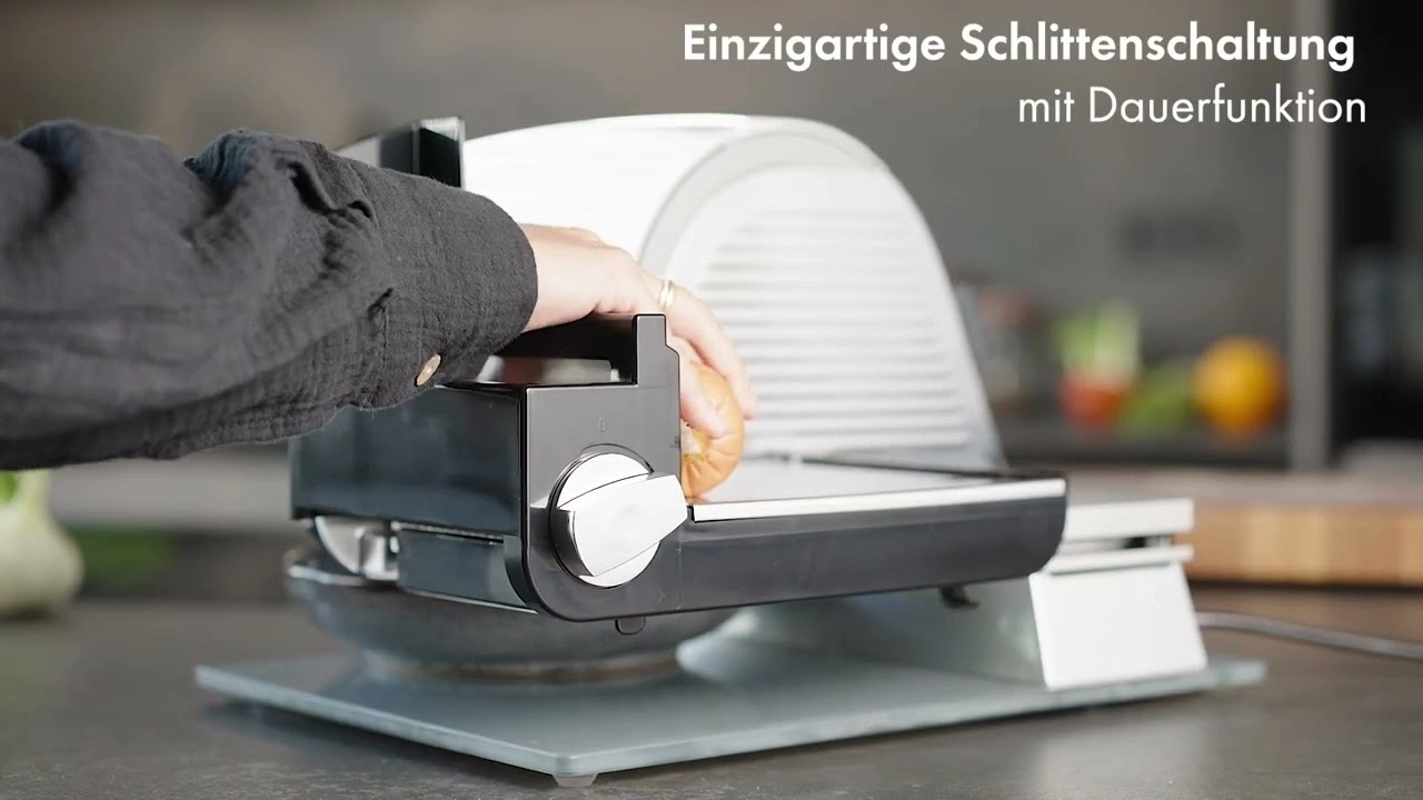 Person slicing bread with a slicer in the kitchen.