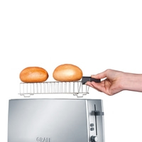 Grille-pain avec accessoire à pain et deux petits pains tenus par une main.