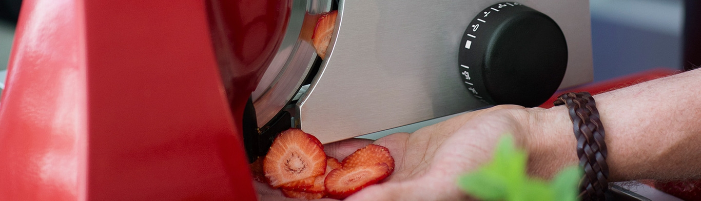 Erdbeeren werden mit einer Maschine geschnitten, Nahaufnahme, Hand, Armband