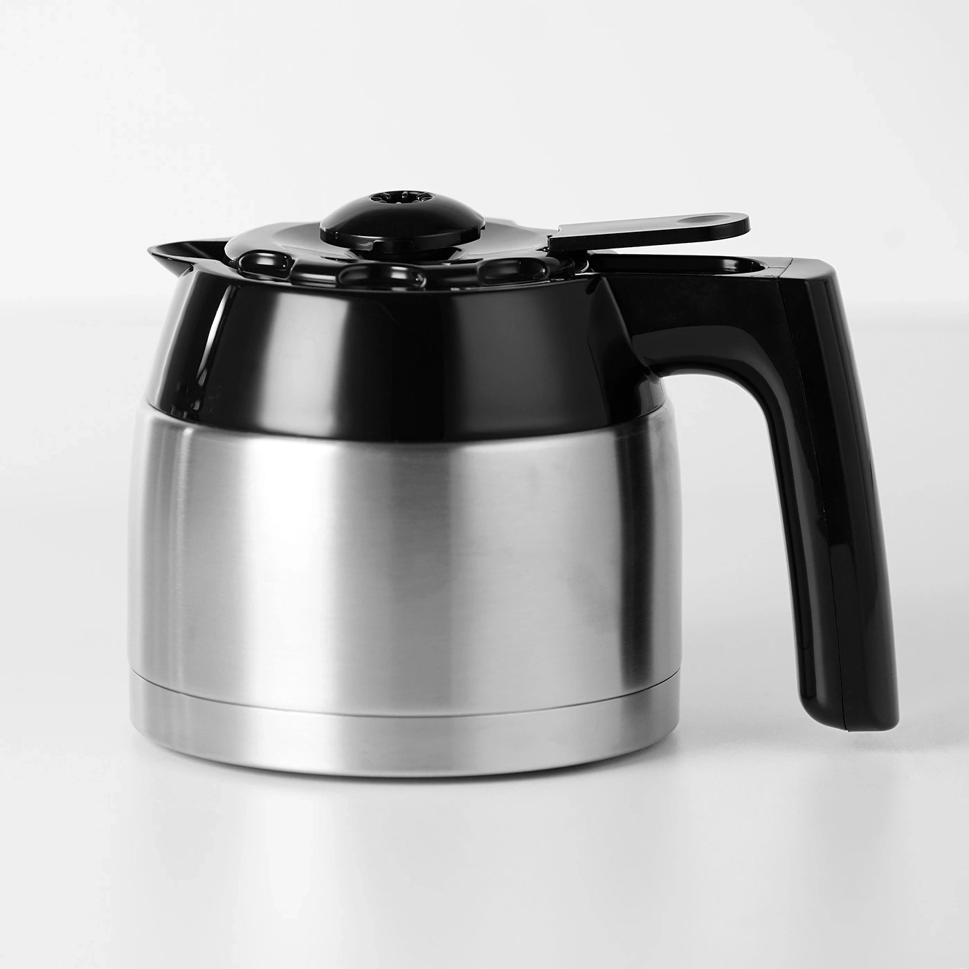 Caffettiera in acciaio inossidabile con coperchio e manico neri su sfondo bianco