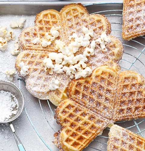 Gaufres en forme de cœur avec pop-corn et sucre glace sur une grille