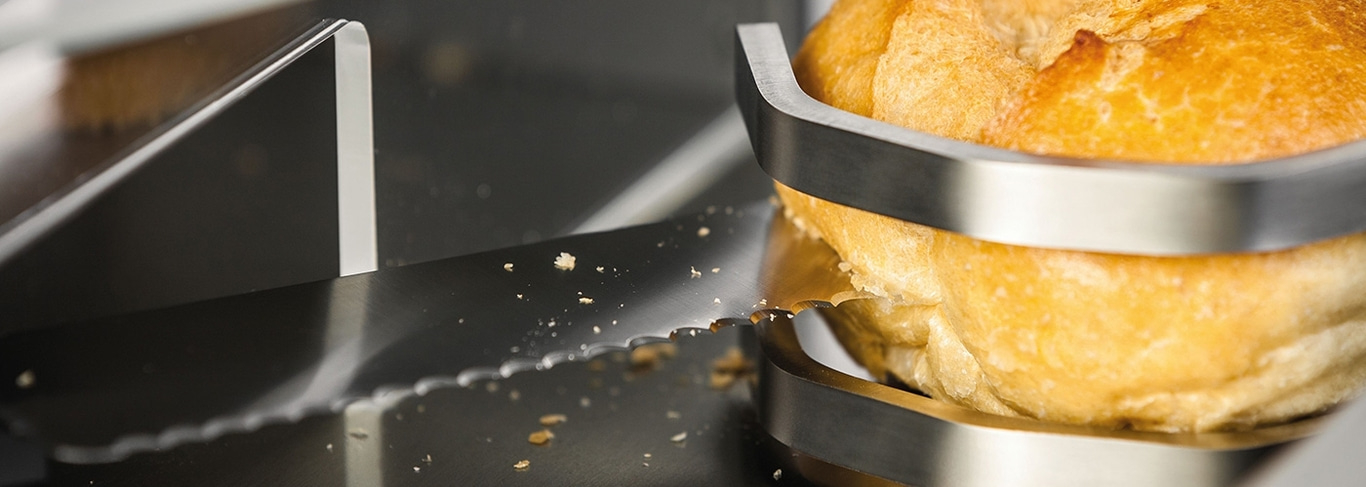 Brot wird mit einem Brotschneider geschnitten, Nahaufnahme, Detailaufnahme, scharf