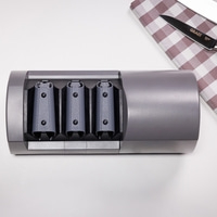 Affilacoltelli grigio con tre fessure e un coltello su un panno a scacchi.