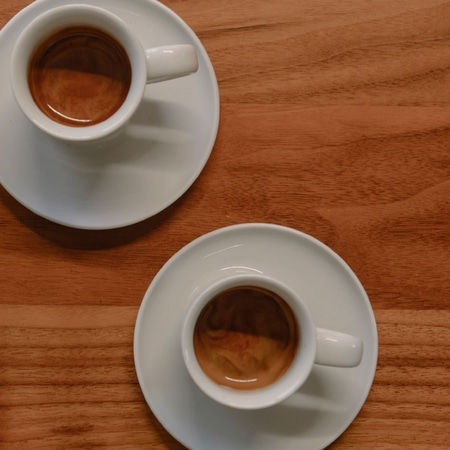 Zwei Kaffeetassen auf Untertassen auf einem Holztisch, Nahaufnahme.