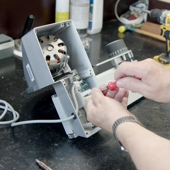 Personne réparant un appareil avec un tournevis, gros plan, atelier, technologie