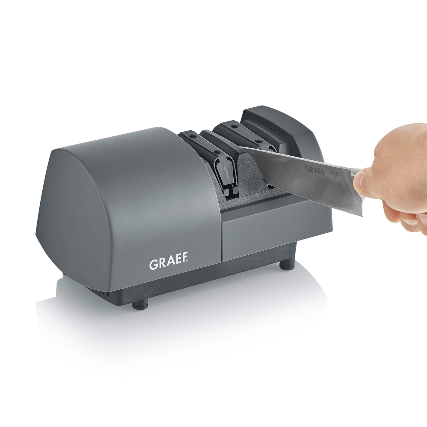 Graef knife sharpener, gray device, knife being sharpened, hand holding knife