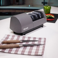 A Graef electric knife sharpener with two knives on a checkered cloth.