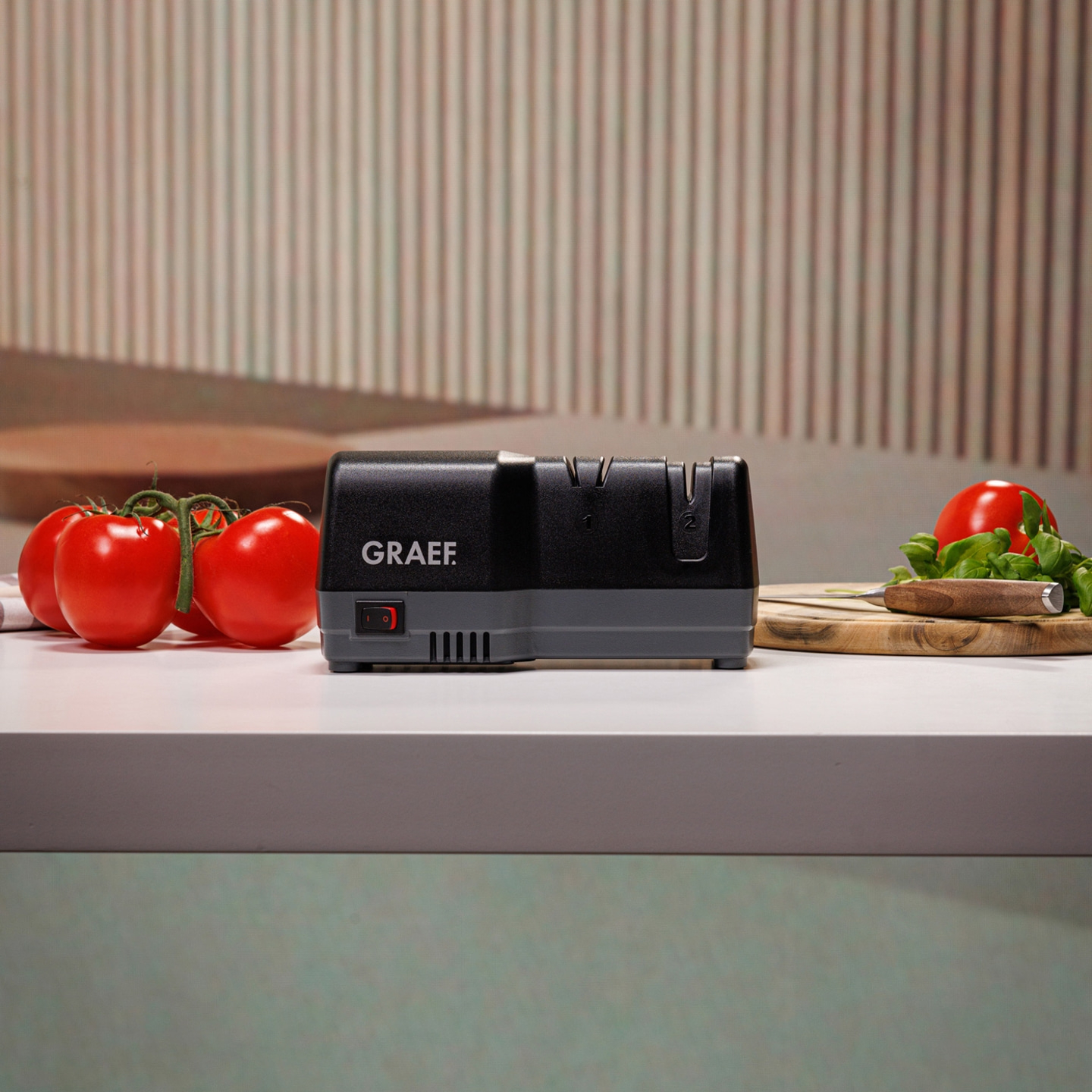 Kitchen scene: tomatoes, knife, cutting board, and electric knife sharpener.