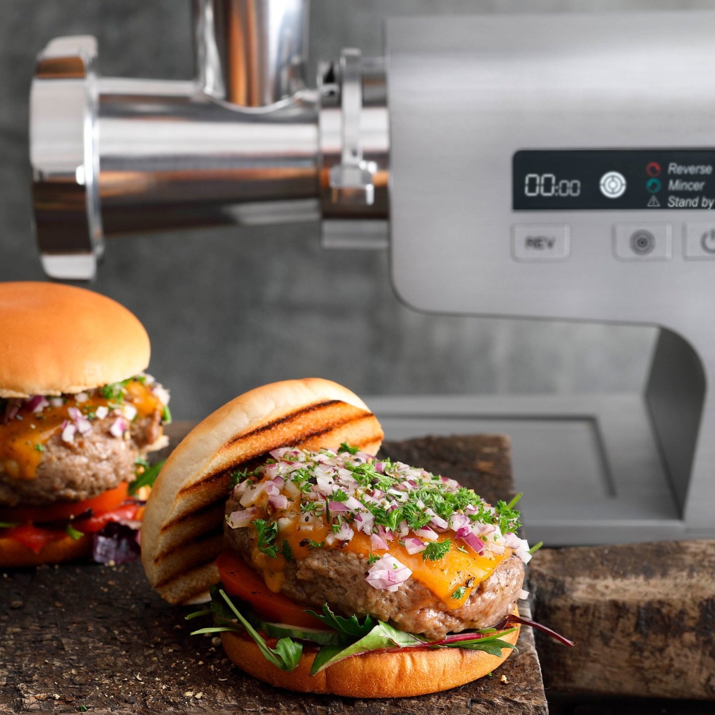 Burgers with cheese and onions in front of a meat grinder machine