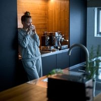 Donna che beve caffè in cucina, rilassata e accogliente al mattino.