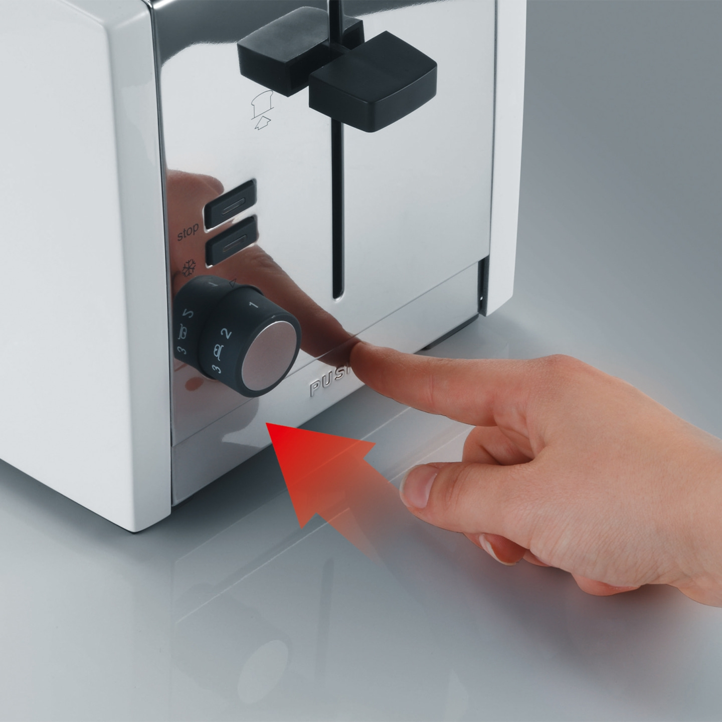 Gros plan d'un grille-pain avec un doigt pointant vers un bouton sur le côté.