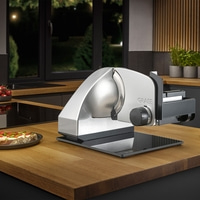 A Graef slicer on a wooden counter with a sandwich next to it.