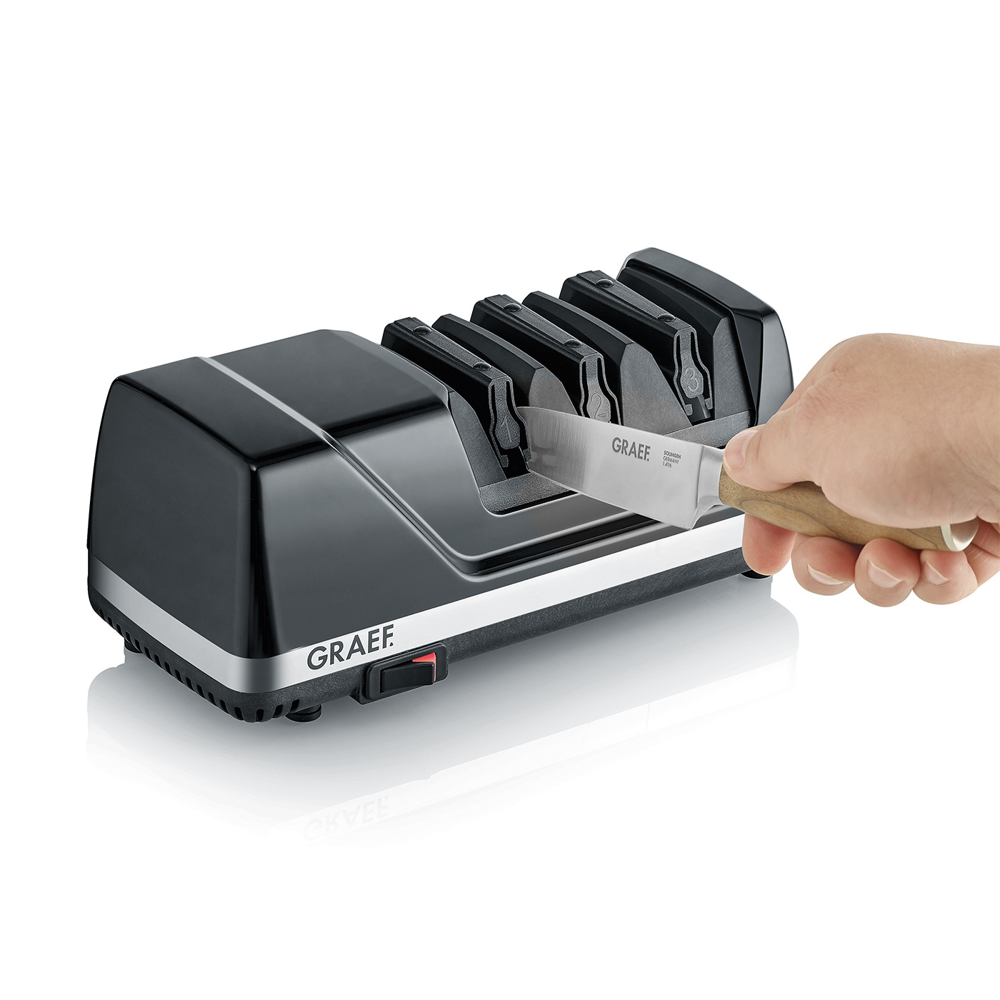 Black electric knife sharpener with knife and hand, GRAEF logo visible