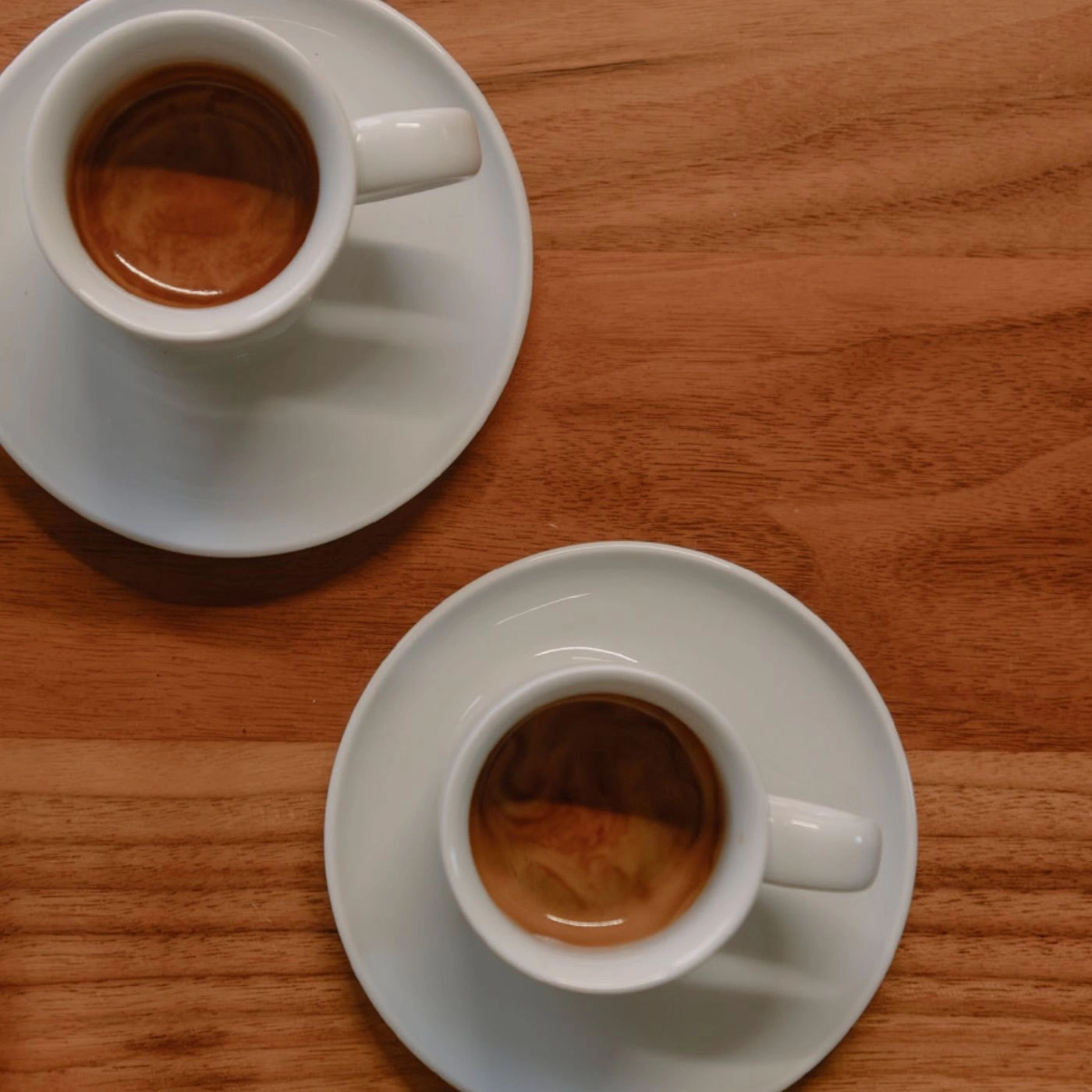 Zwei Kaffeetassen auf Untertassen auf einem Holztisch, Nahaufnahme.