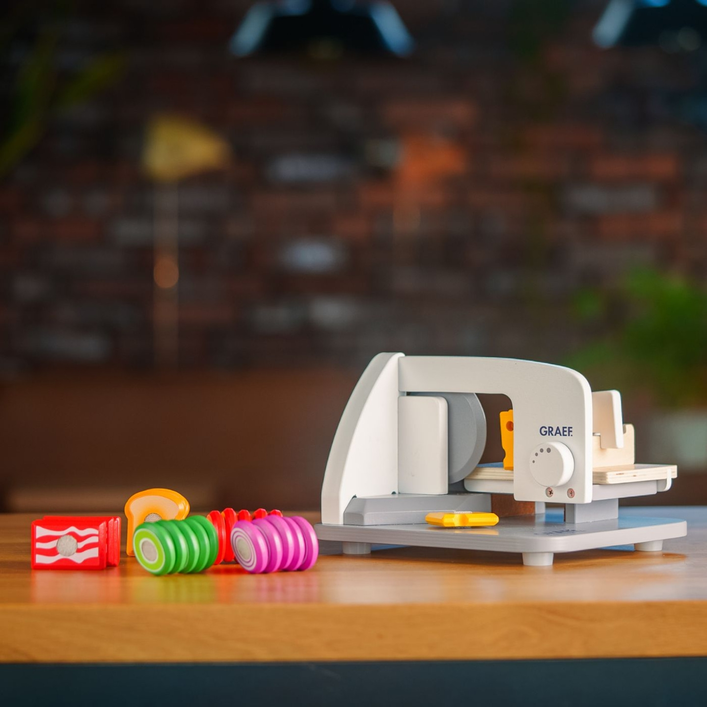Toy food slicer with toy food on a wooden table, a playful scene
