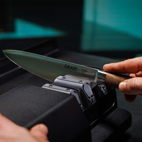 Coltello in affilatura. Coltello GRAEF. Solingen, Germania. Manico in legno. Affilatore. Primo piano.