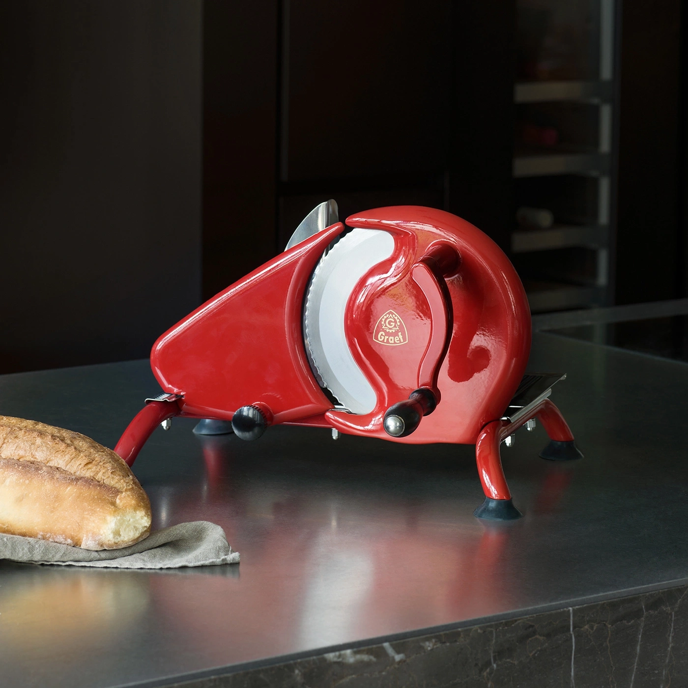 Une trancheuse à pain Graet rouge avec une miche de pain sur un tissu.