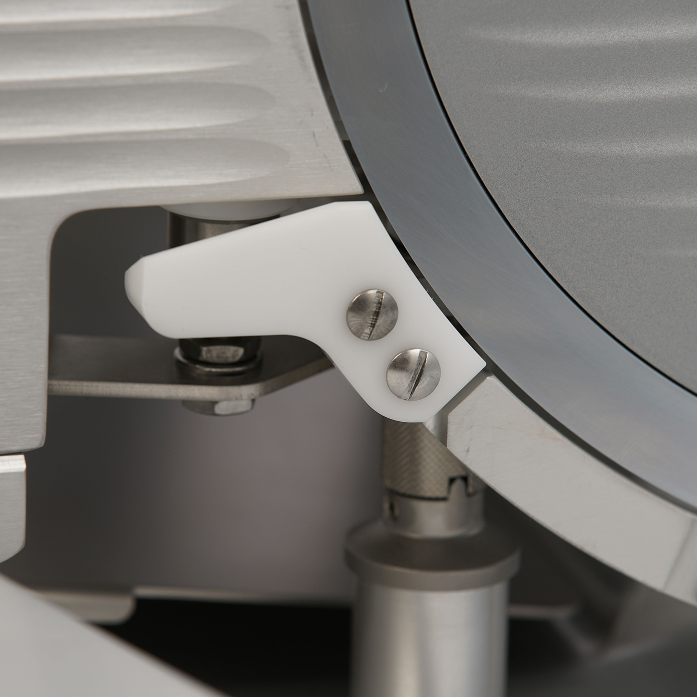 Close-up of a meat slicer with white plastic and metal components