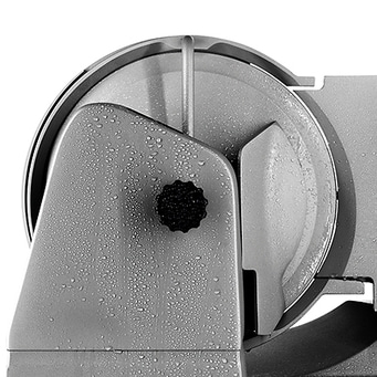 Close-up of a gray meat slicer with water droplets on the surface, wet and clean.