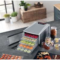 Food dehydrator with fruits and vegetables on a kitchen table, close up.