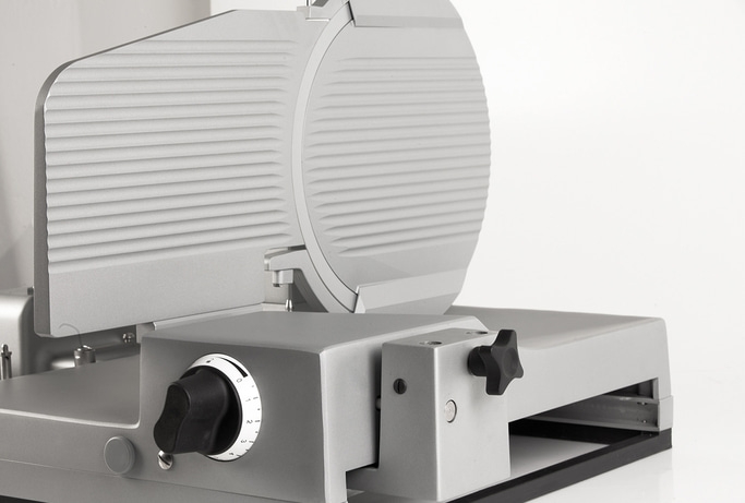 Trancheuse à viande, grise, avec cadran de réglage et lame, gros plan, isolé