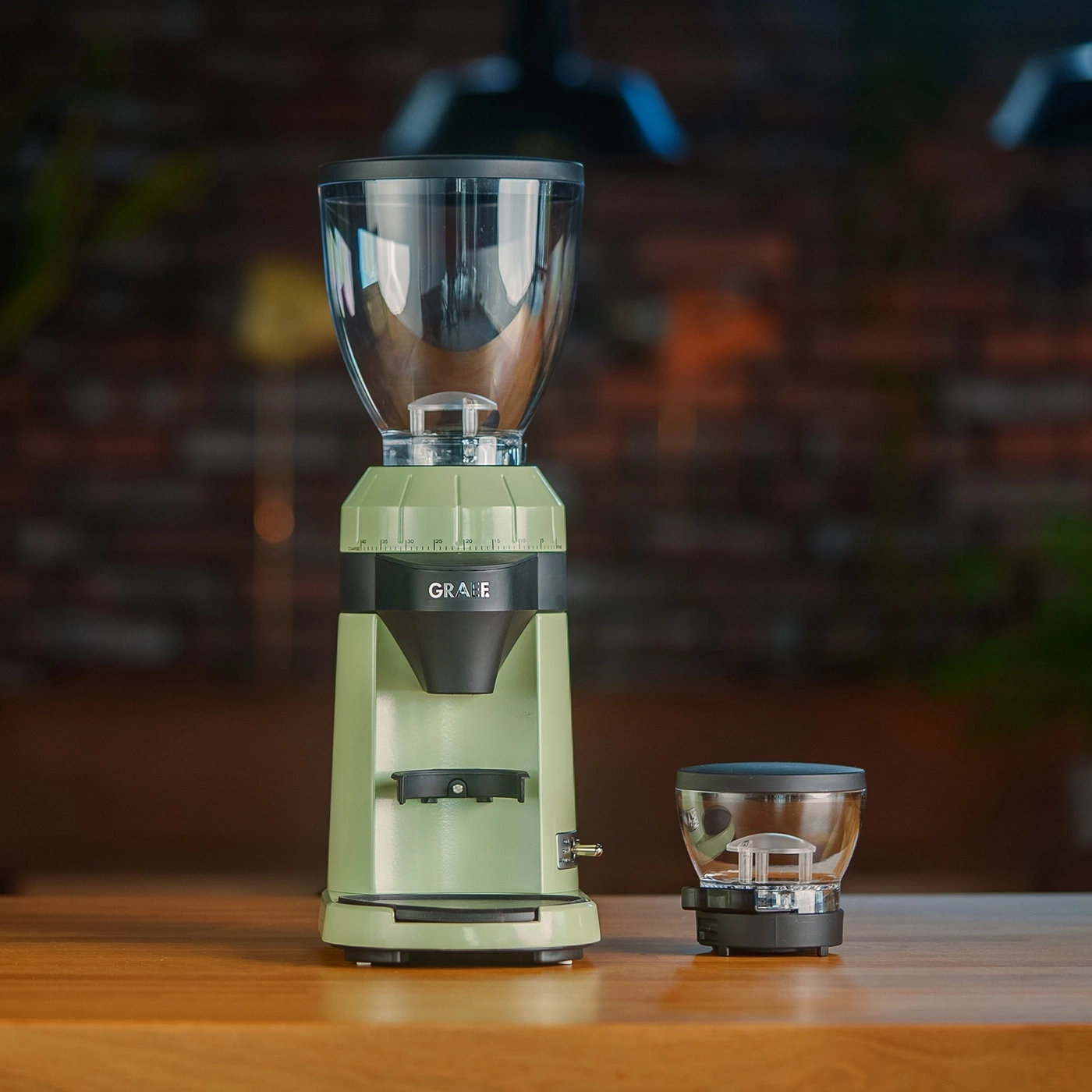 Un macinacaffè elettrico Graef verde chiaro con accessori su un tavolo di legno.
