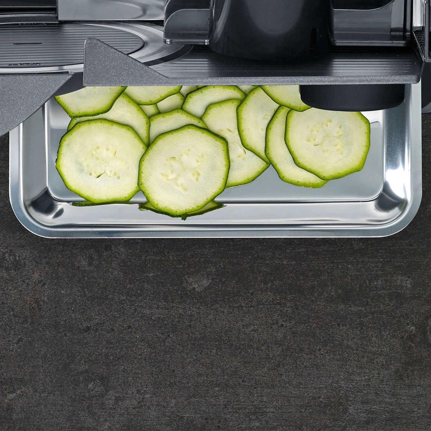 Tranches de courgettes fines dans un plateau en métal, prêtes à être cuisinées.
