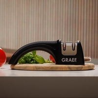 Affûteur de couteaux noir avec légumes sur une planche de bois