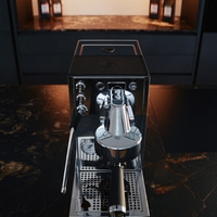 A shiny espresso machine on a dark marble countertop in a modern kitchen.