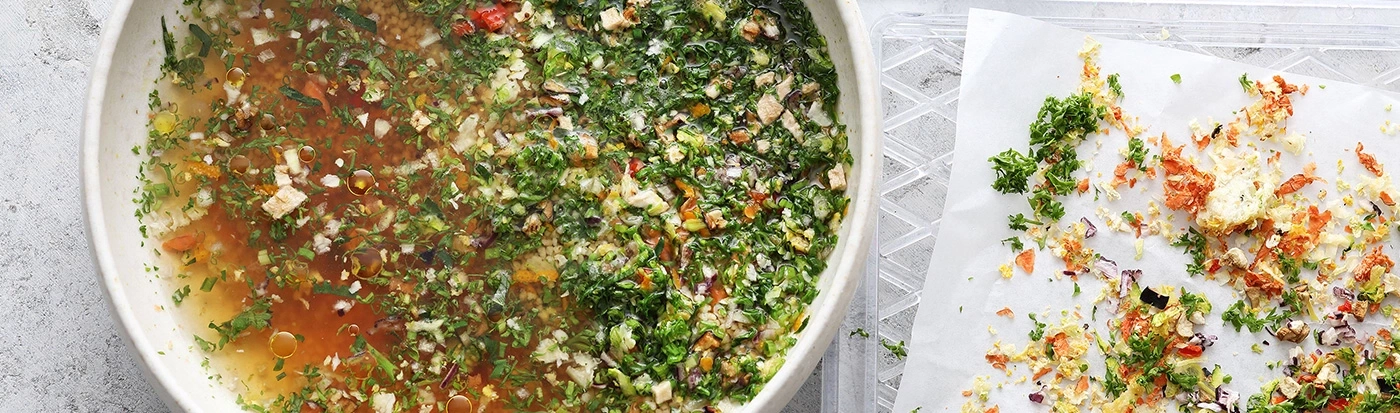 Bol de soupe et de légumes, avec des légumes sur du papier à côté