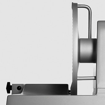 Close-up of a silver meat slicer against a white background, kitchen appliance