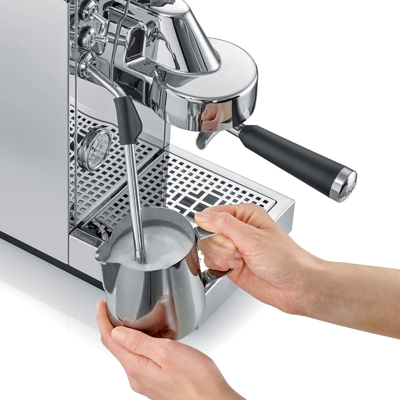 Une personne fait mousser du lait dans un pichet en acier inoxydable avec une machine à expresso.
