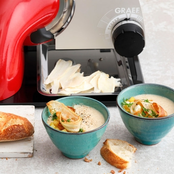 Soupe avec du pain et des légumes, servie avec une trancheuse.