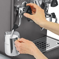 Persona che prepara il latte su una macchina da caffè per fare il caffè, schiumando il latte.