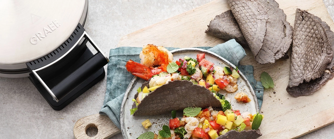 Tacos di gamberi grigliati con salsa di mango su un piatto con tortillas