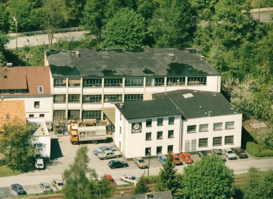 Vue aérienne de bâtiments avec des arbres et des voitures garées à proximité.