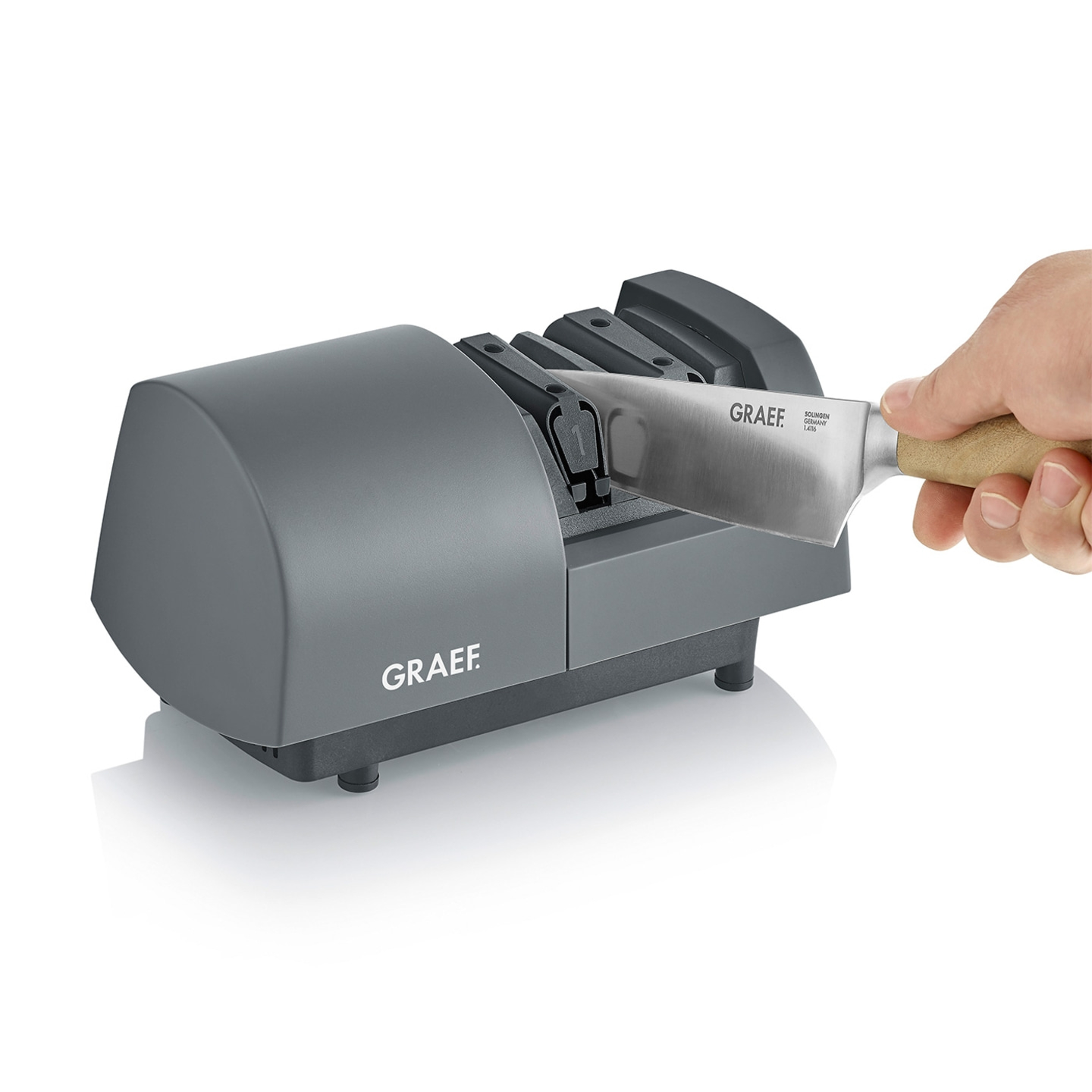 Knife sharpener with knife, hand holding knife, gray machine, white background