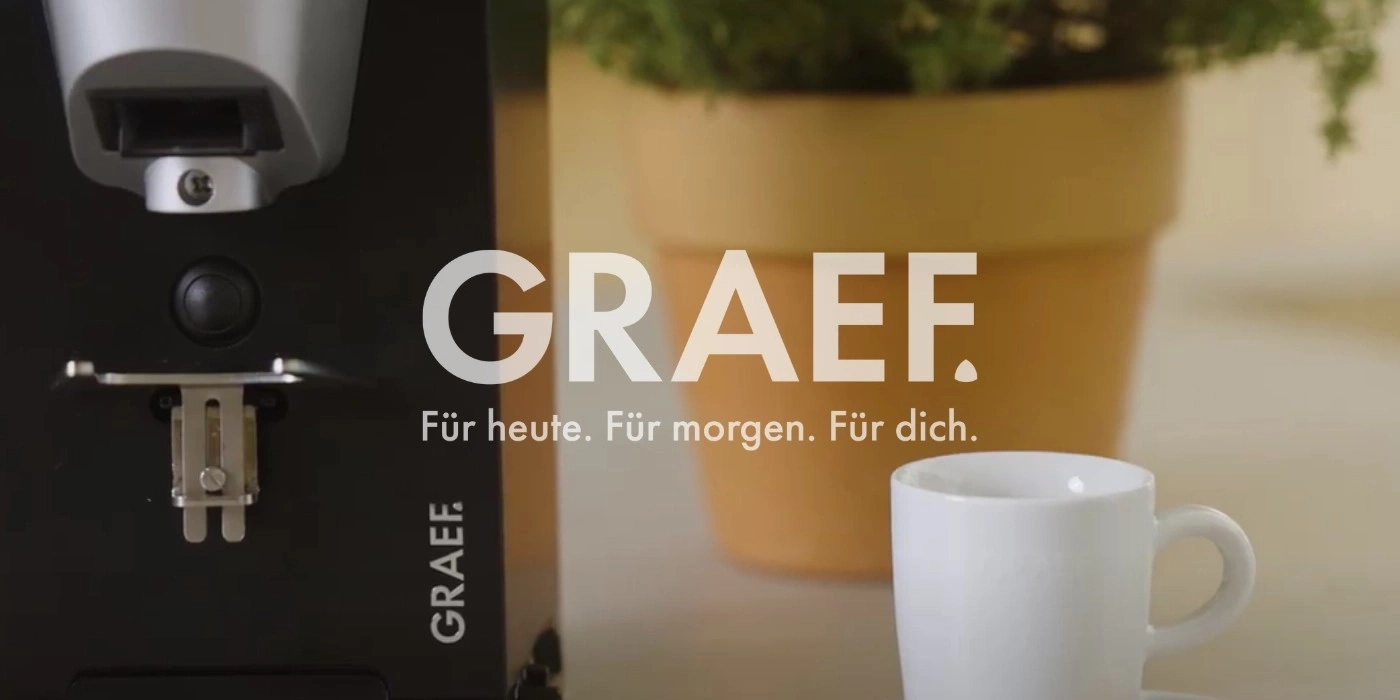 Macchina da caffè con tazza e vaso con pianta, logo GRAEF