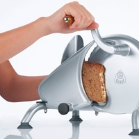 Personne coupant du pain avec une trancheuse, gros plan, logo Graet, machine argentée