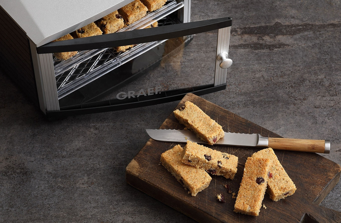 A food dehydrator with bars and a knife on a wooden board.