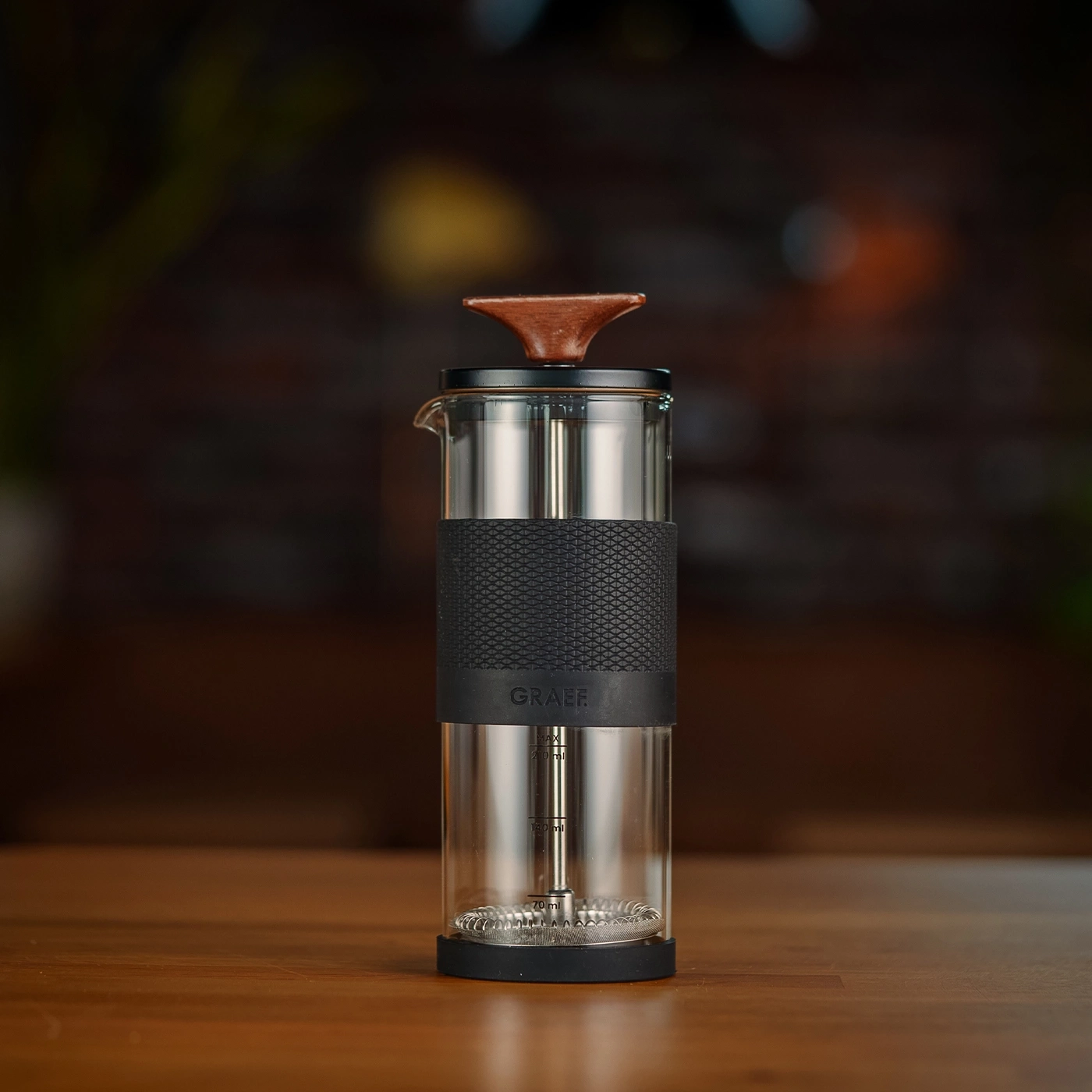 Cafetière en verre avec poignée en bois et bande noire, marque GRAEF visible.