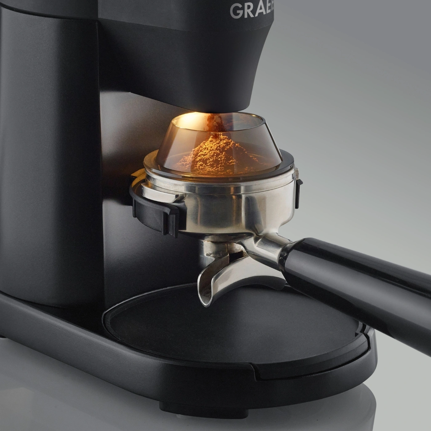 Macinacaffè con polvere di caffè e portafiltro, primo piano, nero