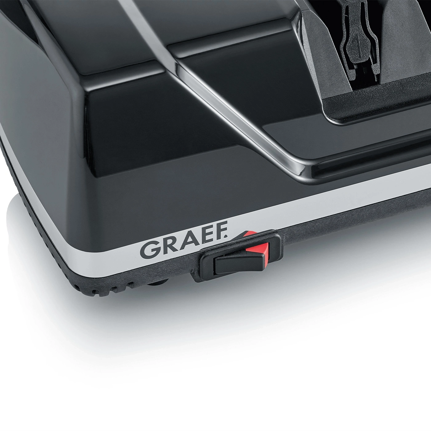 Primo piano di un dispositivo nero con logo GRAEF e interruttore rosso, superficie lucida.